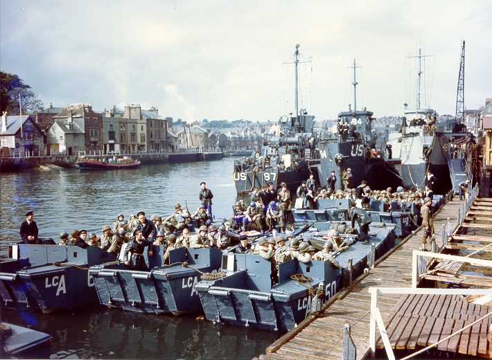Coast Guard Flotilla 10 tied up in the background along with British landing craft, prepare to sail the English Channel and invade Nazi-occupied France. These landing craft landed U.S. troops on Omaha Beach.